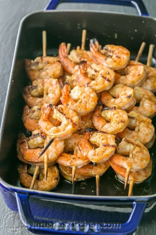grilled garlic cajun shrimp skewers stacked in a blue baking dish