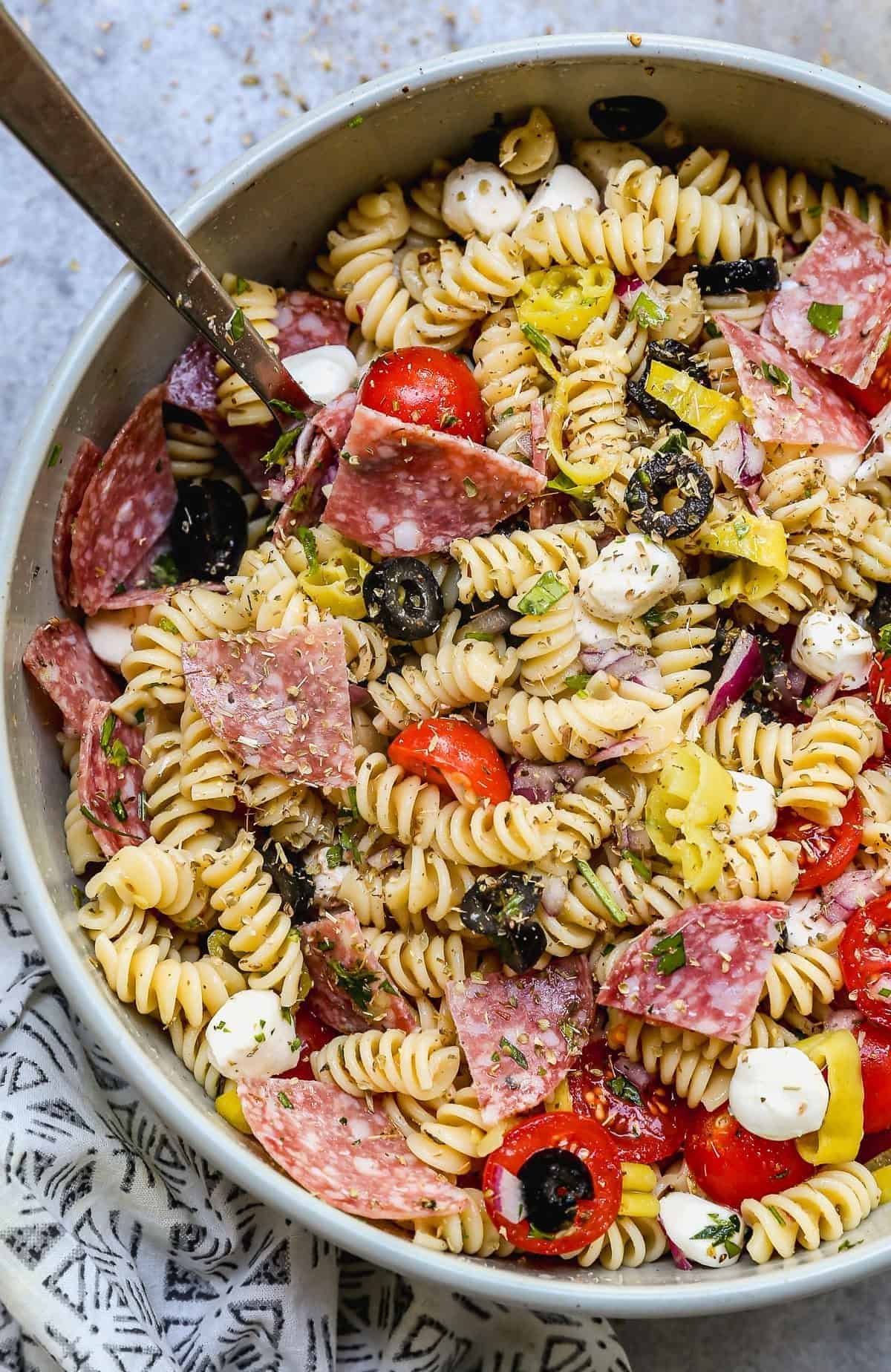 italian pasta salad with rotini, salami, tomatoes, black olives, and mozzarella in a bowl.