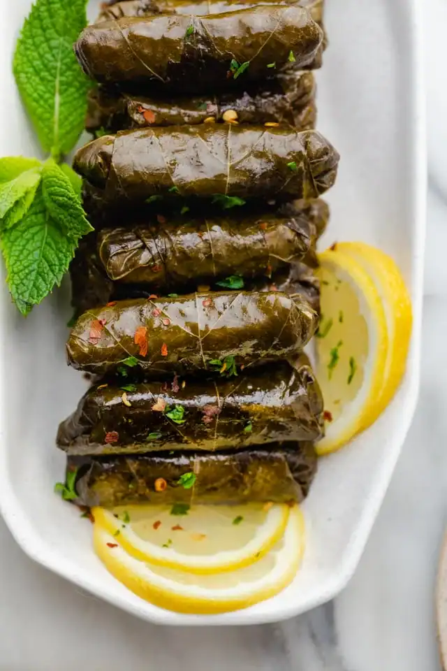 lebanese stuffed grape leaves garnished with lemon slices and fresh mint leaves