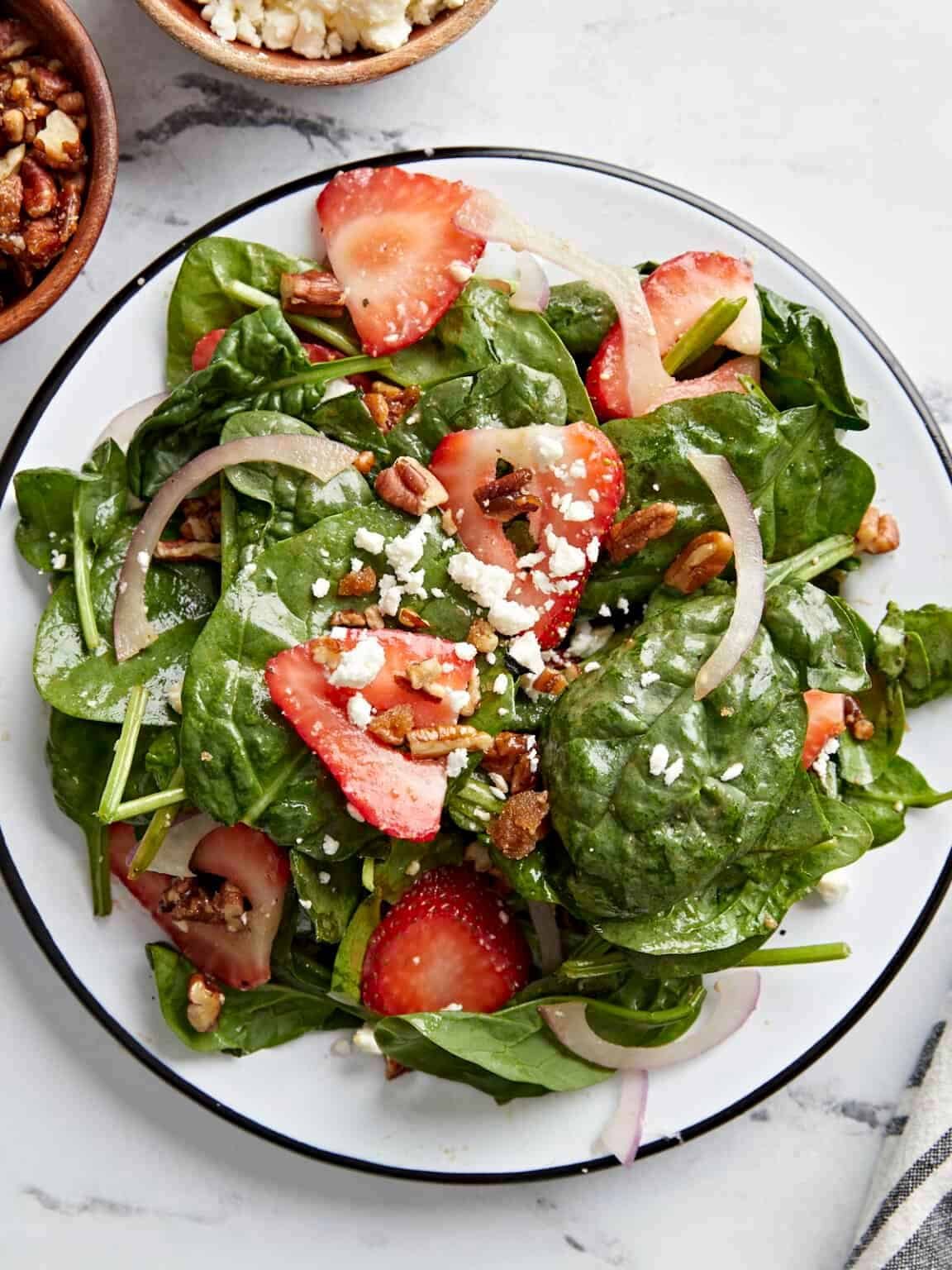 strawberry spinach salad with crumbled feta cheese, pecans, and sliced red onions.
