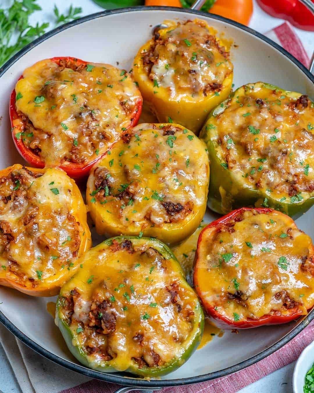 stuffed peppers topped with melted cheese and fresh parsley in a white baking dish.
