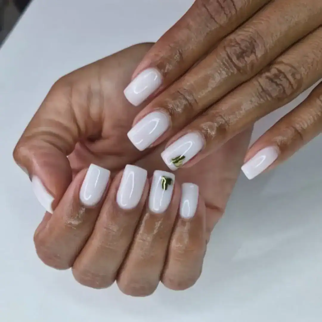 square, clean white fingernails with a gold heart detail on two fingers
