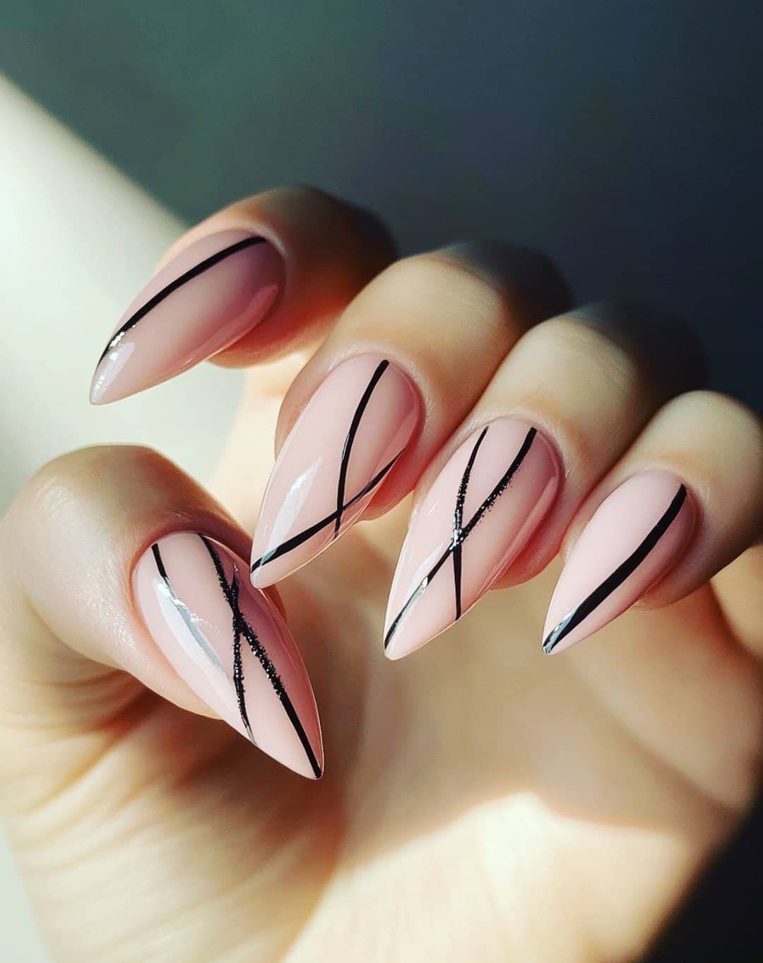 almond shaped nails with a clean, light pink finish and thin black diagonal lines
