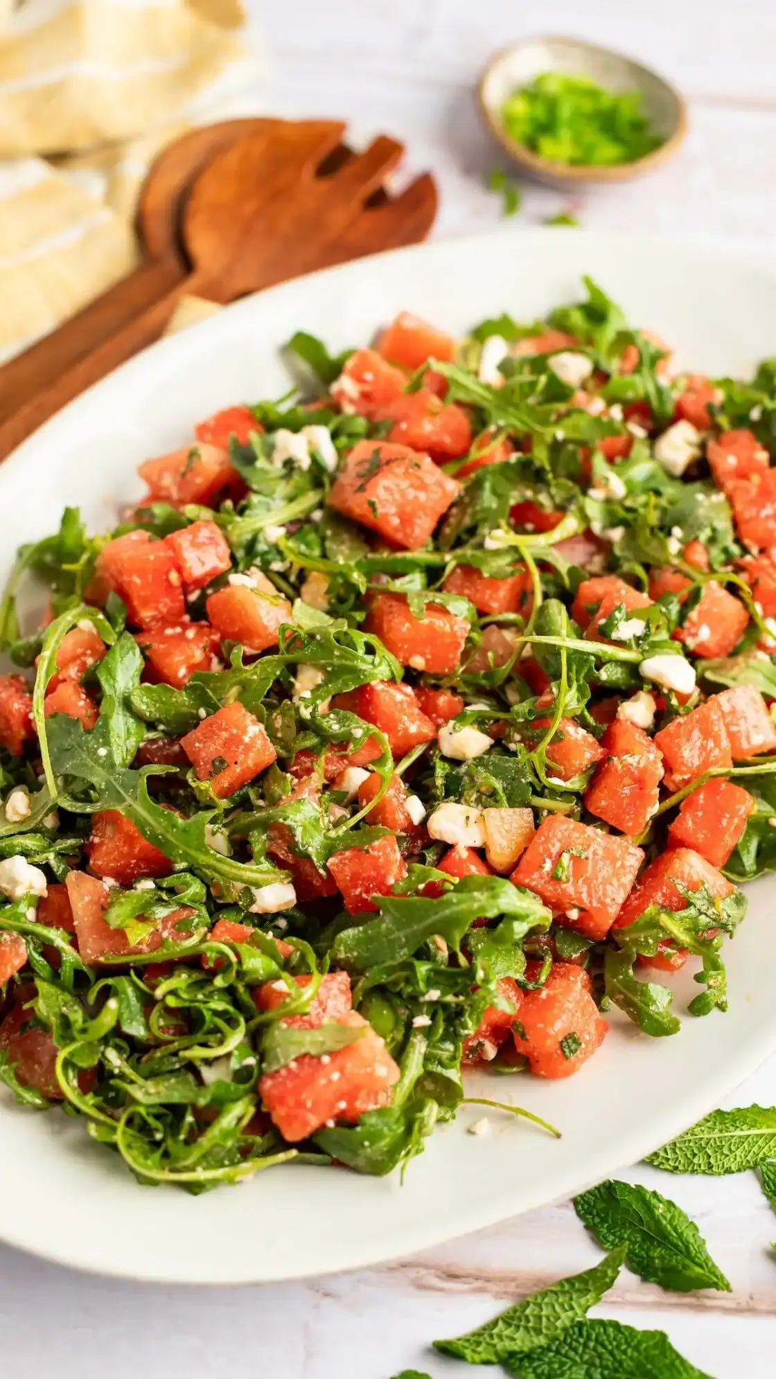 watermelon feta salad with fresh arugula, mint leaves, and balsamic glaze in a bowl.