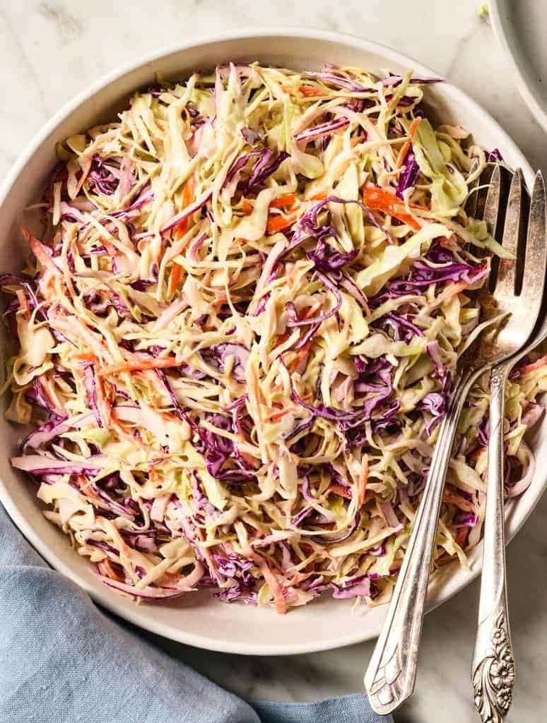 creamy coleslaw made with shredded red and green cabbage in a white bowl.