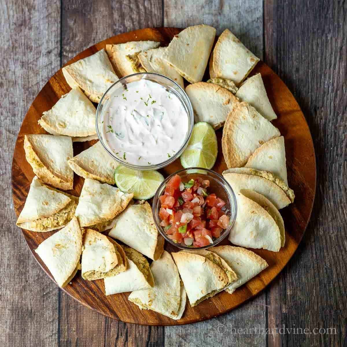 mini chicken quesadillas on a wooden platter with salsa and dipping sauce
