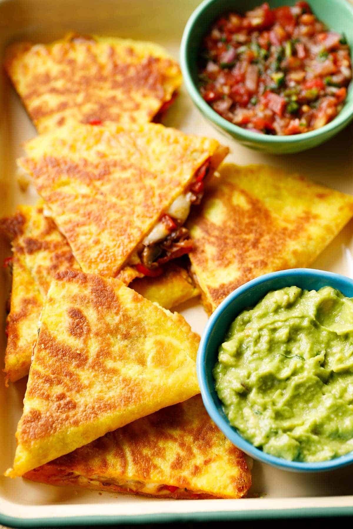 golden brown quesadillas served with bowls of chunky tomato salsa and creamy guacamole.