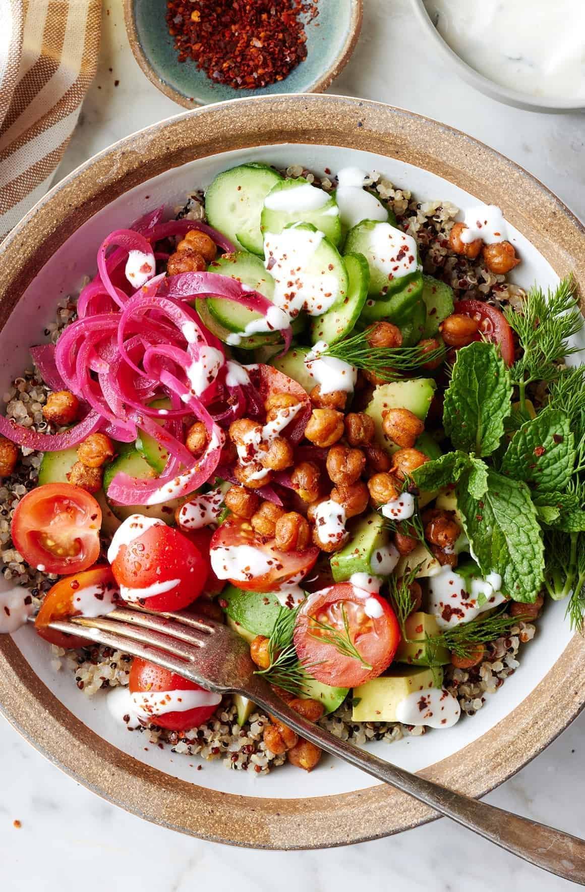 quinoa bowl recipe with roasted chickpeas, cucumbers, tomatoes, and pickled onions.
