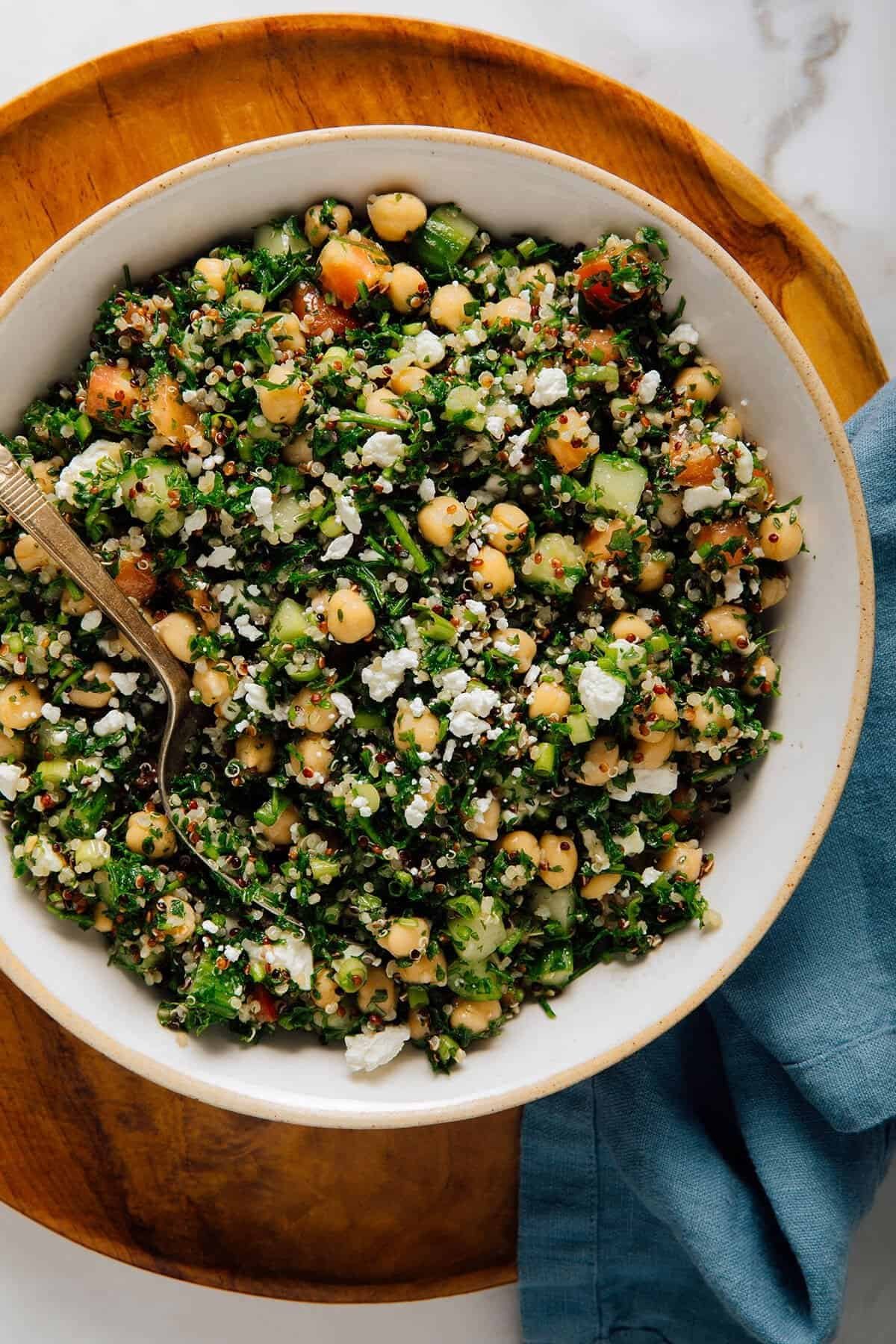 quinoa tabbouleh salad with chickpeas, cucumber, feta cheese, and fresh herbs in a bowl.
