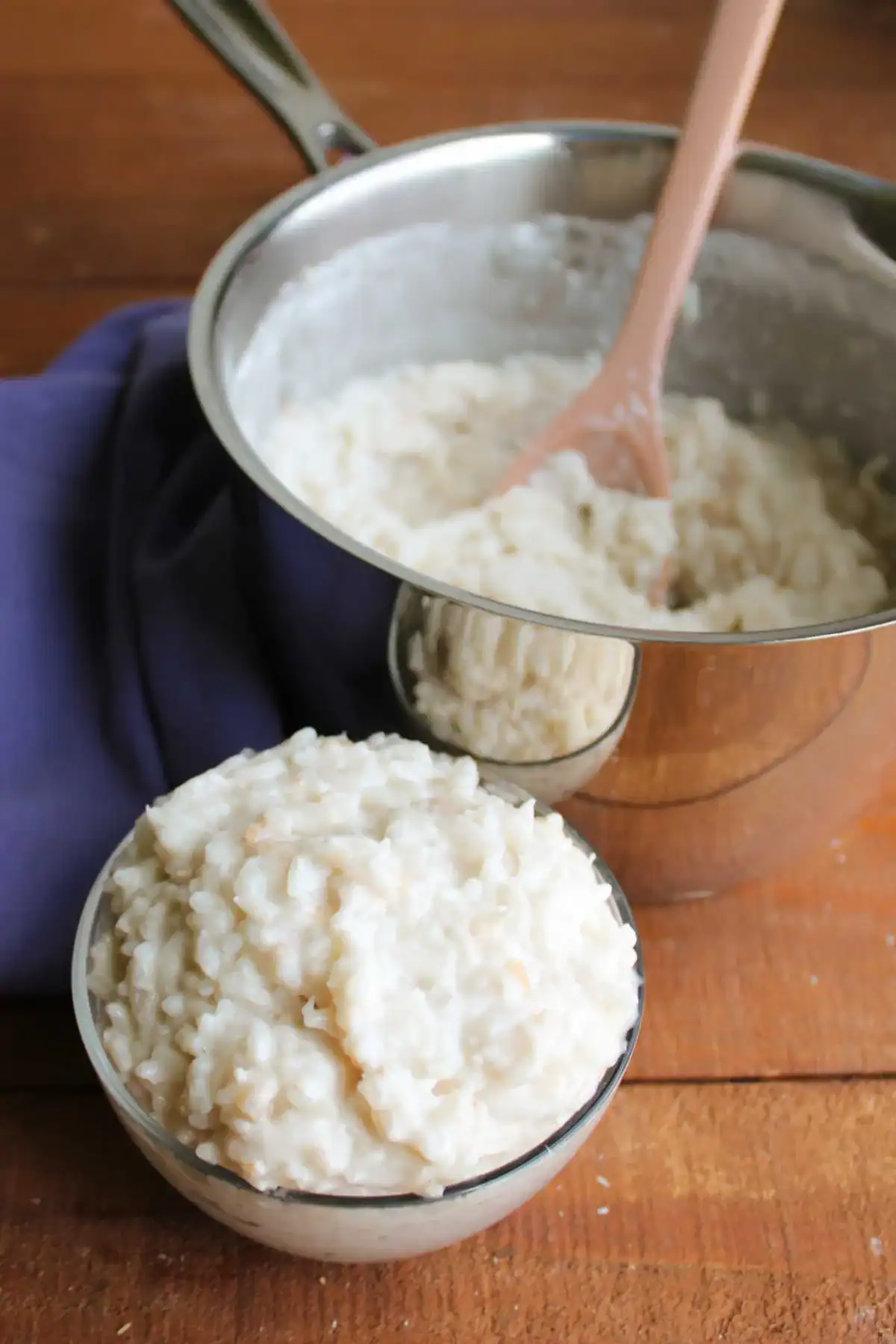a small glass bowl of creamy coconut rice pudding served alongside a large metal pot