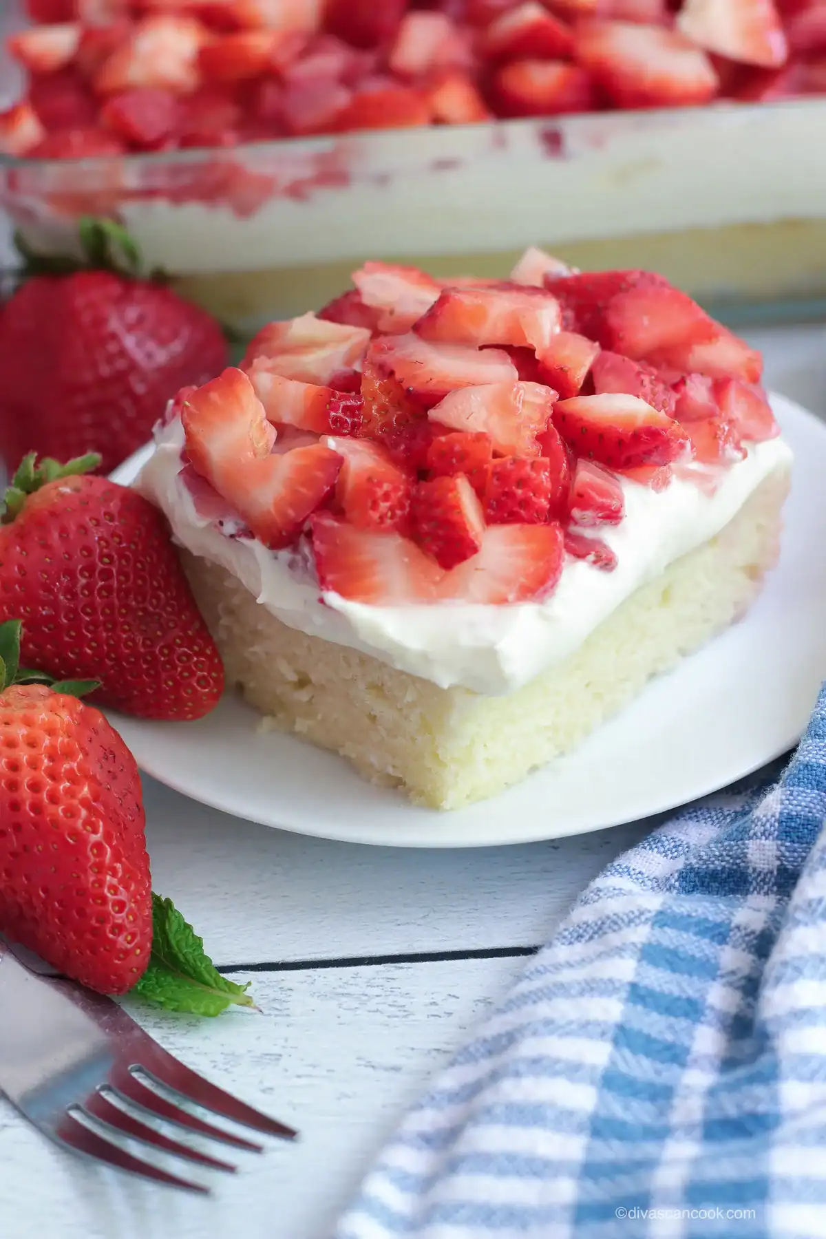 a slice of strawberry shortcake cake topped with fresh chopped strawberries and whipped cream