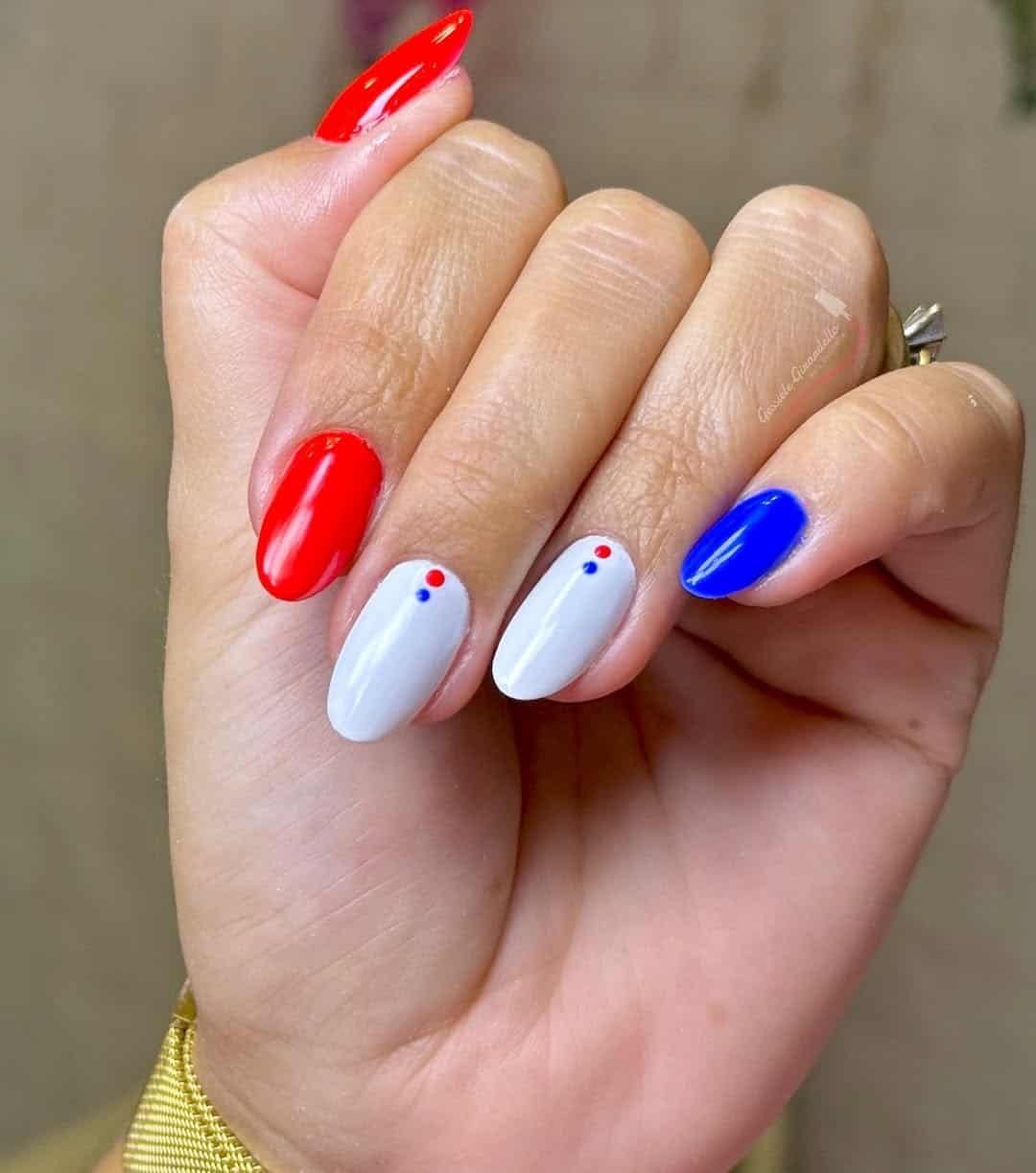 glossy almond nails in red, white, and blue with minimalist dot accents.