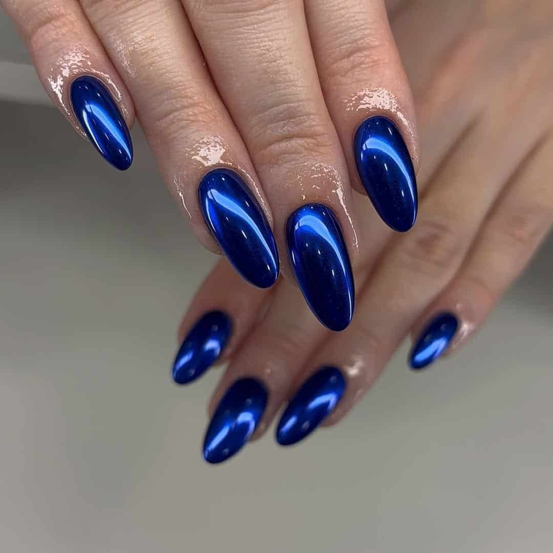 long almond nails with a glossy metallic deep blue chrome finish.