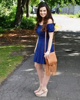 woman in blue off-the-shoulder dress with tan fringe crossbody bag and wedges.