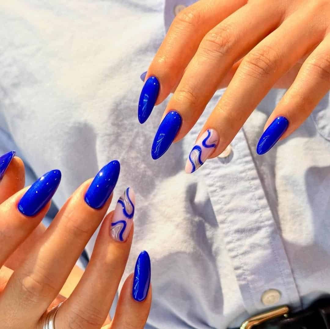 long glossy cobalt blue pointed nails featuring abstract swirl accent nail art designs