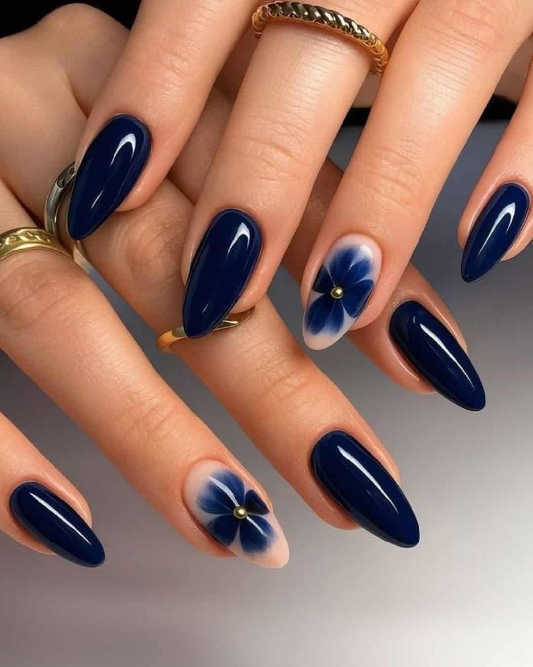 dark navy blue pointed almond nails featuring transparent accent nails with painted blue flowers