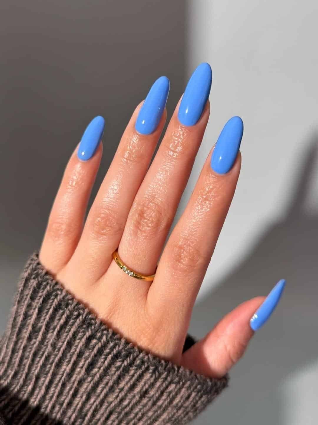 long oval almond shaped nails painted in a bright sky blue glossy color