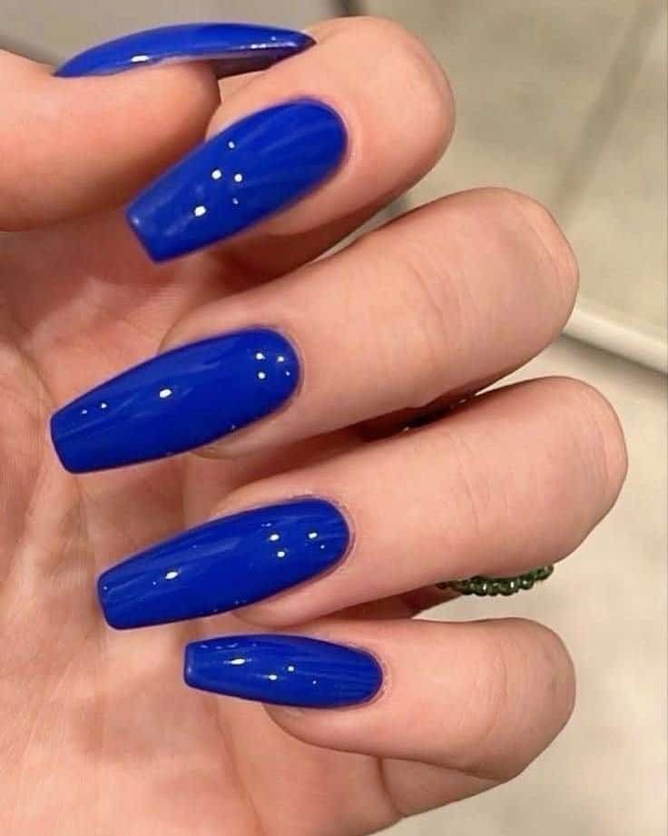glossy electric royal blue square manicure shown up close on a person's hand