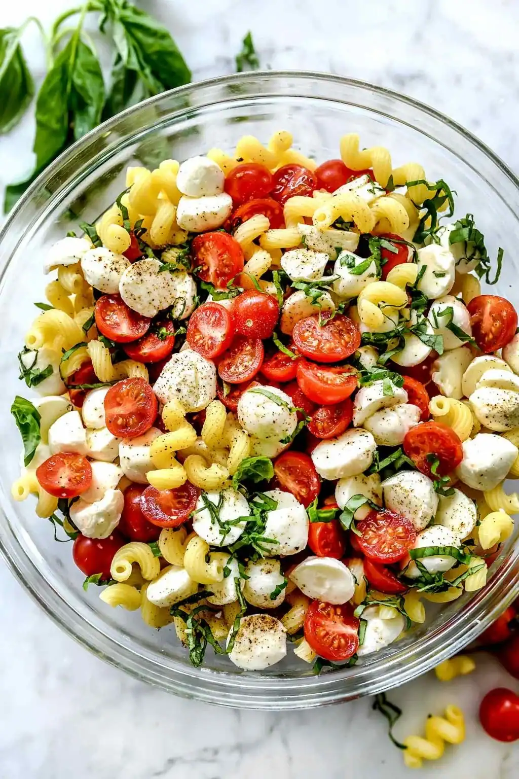 caprese pasta salad with rotelle, fresh mozzarella pearls, cherry tomatoes, and basil leaves