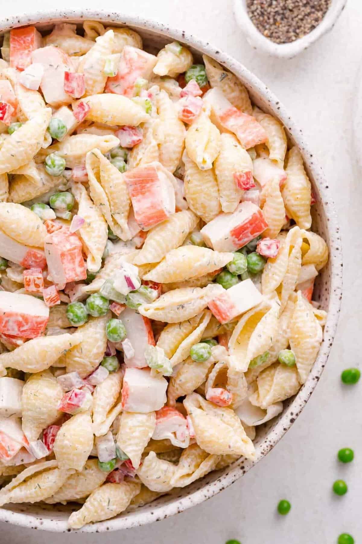 creamy crab pasta salad with shell pasta, imitation crab meat, and green peas