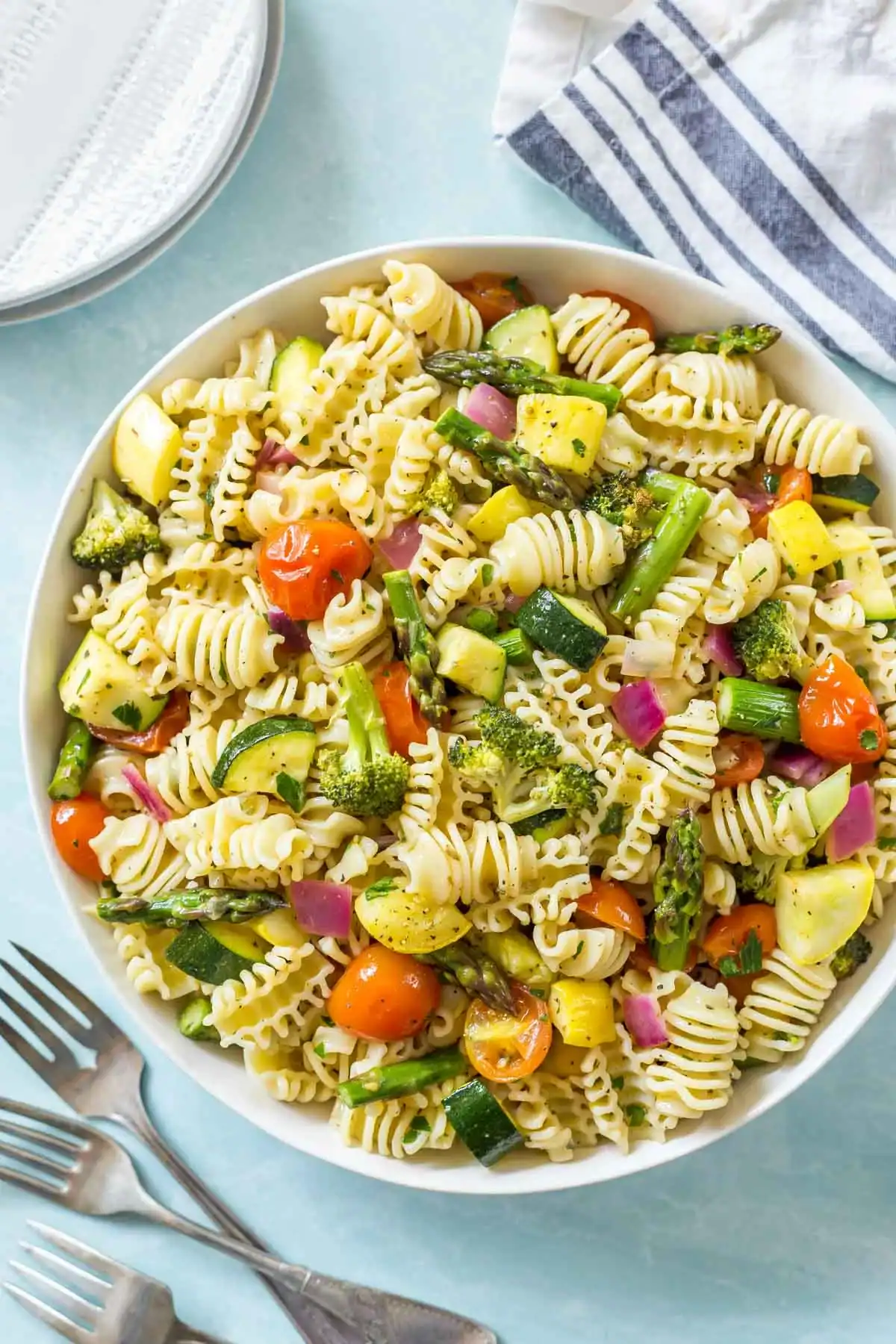 radiatore pasta salad with roasted broccoli, asparagus, tomatoes, and zucchini in a white bowl