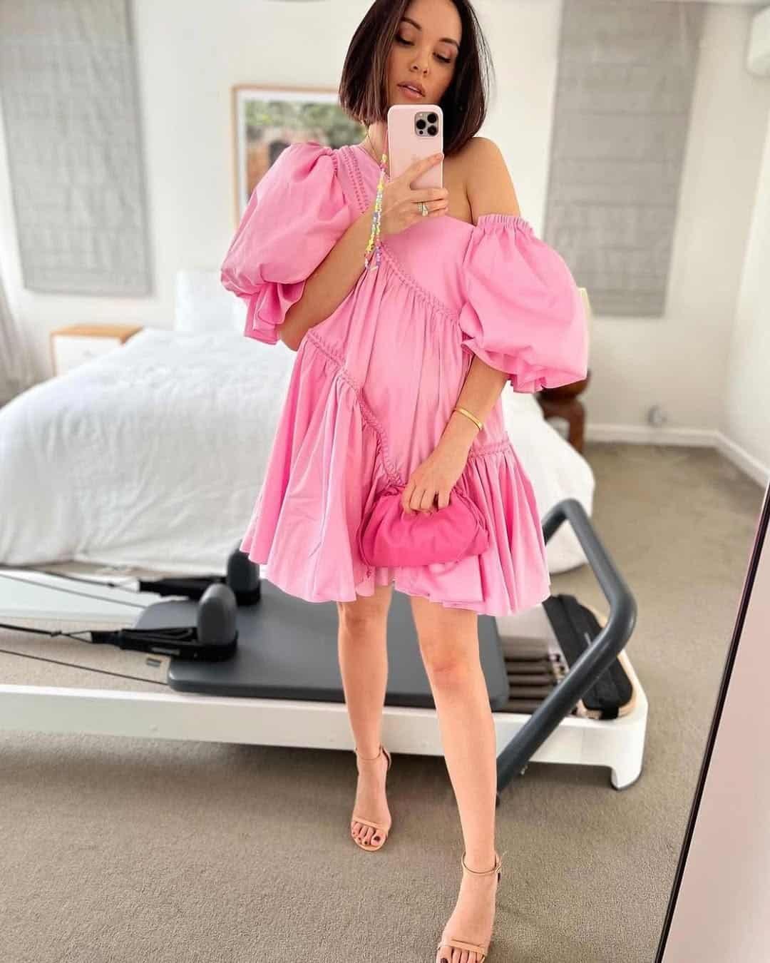 woman in a puffy pink off-the-shoulder mini dress holding a matching clutch