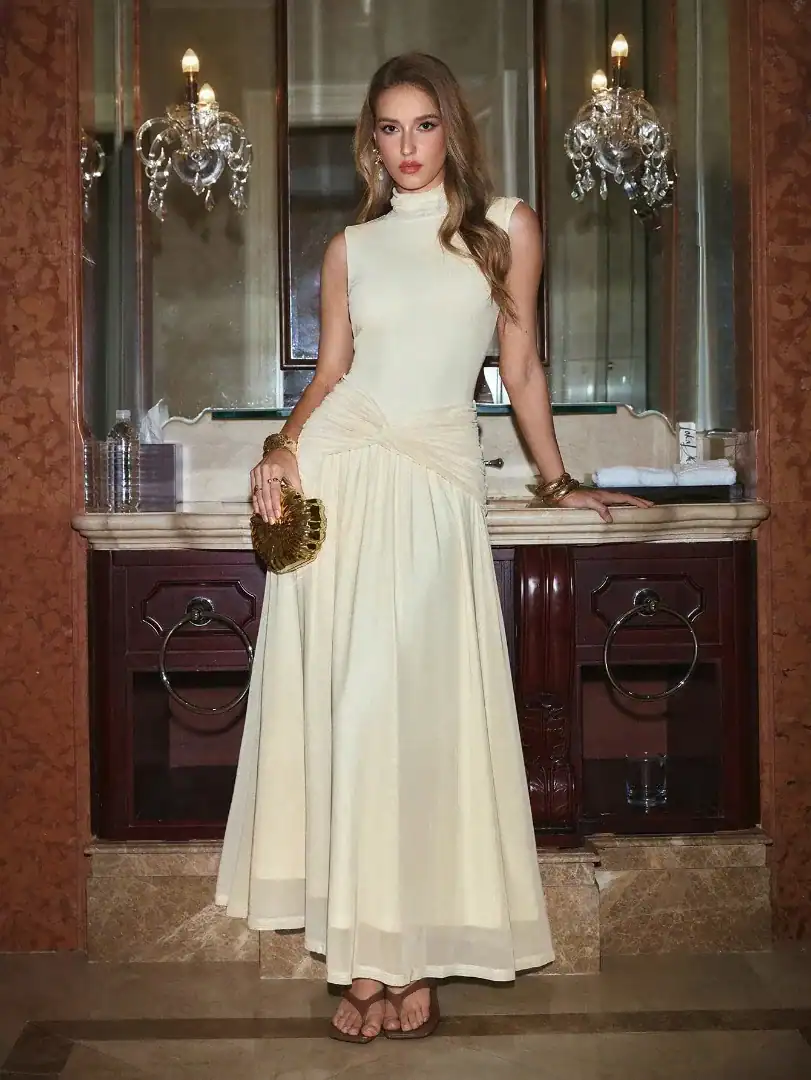 woman standing in front of a mirror wearing a cream sleeveless maxi dress