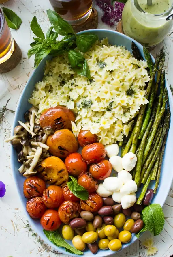 blue platter of summer pasta salad with bow tie pasta, roasted tomatoes, and grilled asparagus
