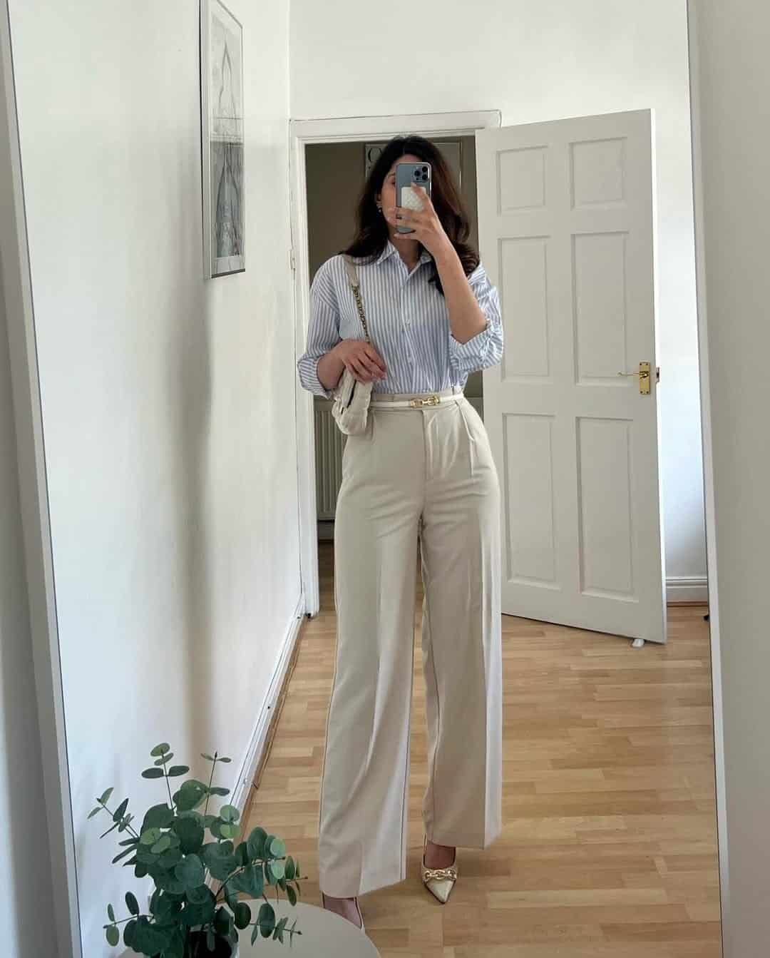 woman wearing blue and white striped button down shirt with cream wide leg trousers