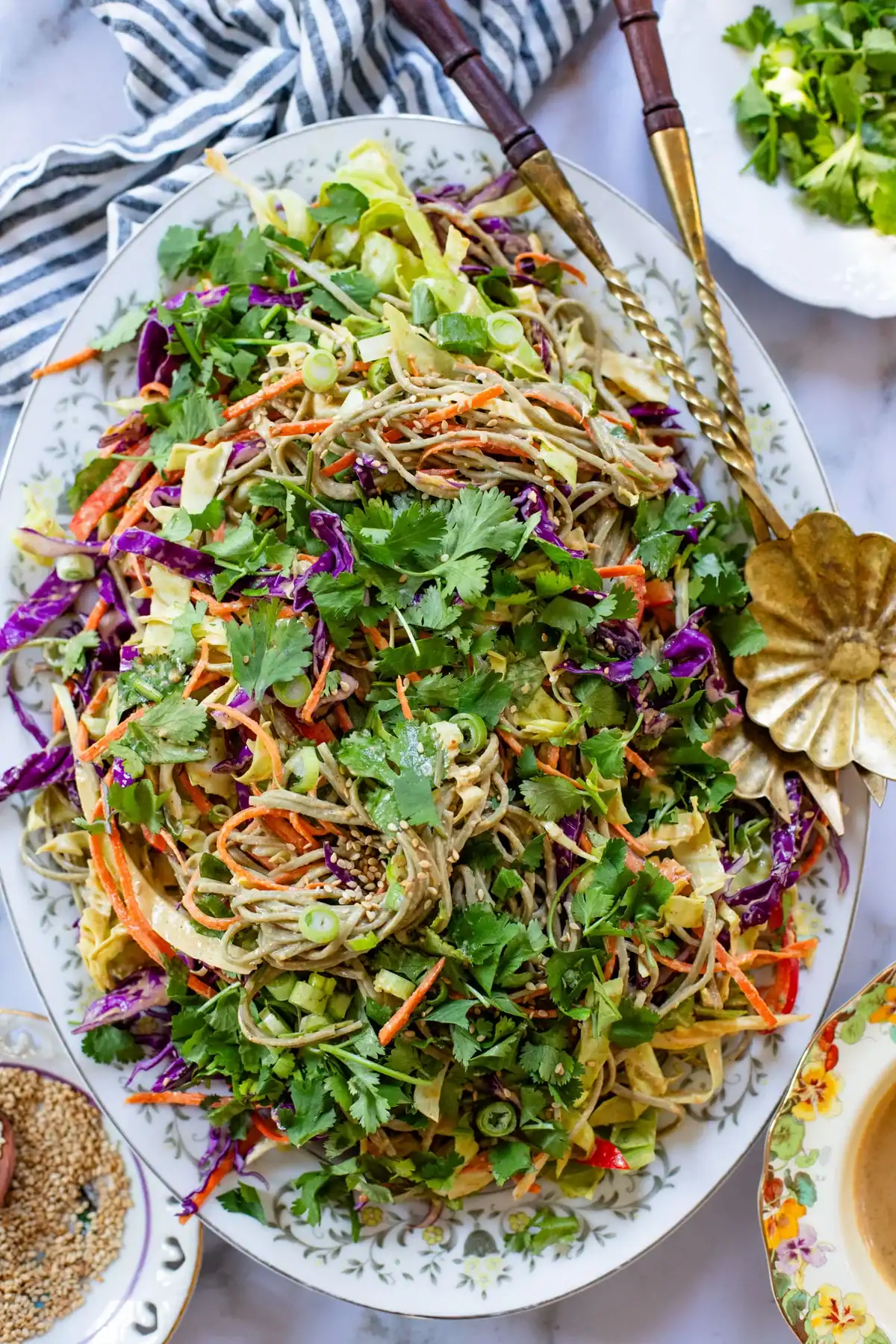 large platter of cold peanut noodle salad with purple cabbage, carrots, and fresh cilantro