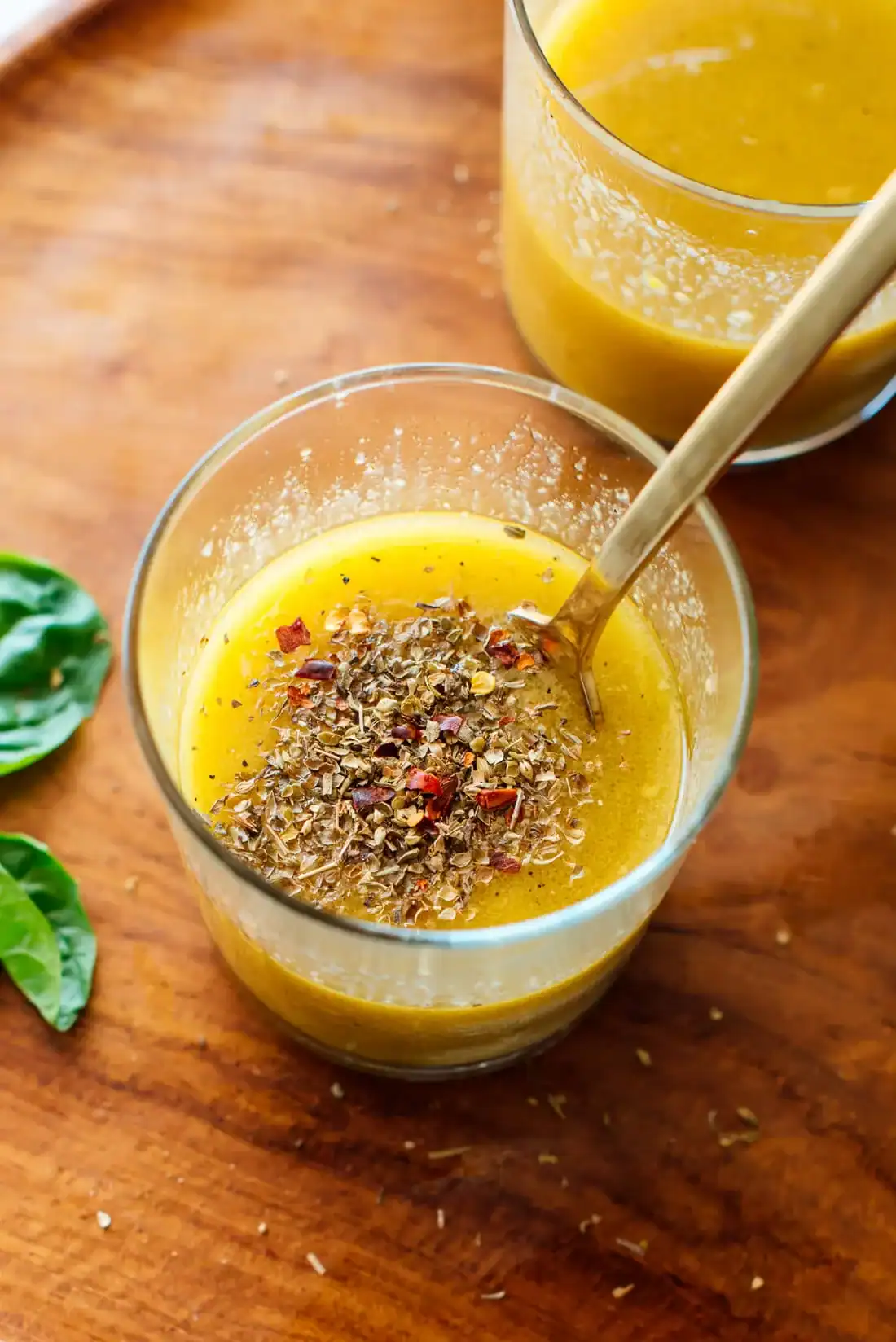 glass jar filled with yellow greek vinaigrette topped with dried herbs and red pepper flakes