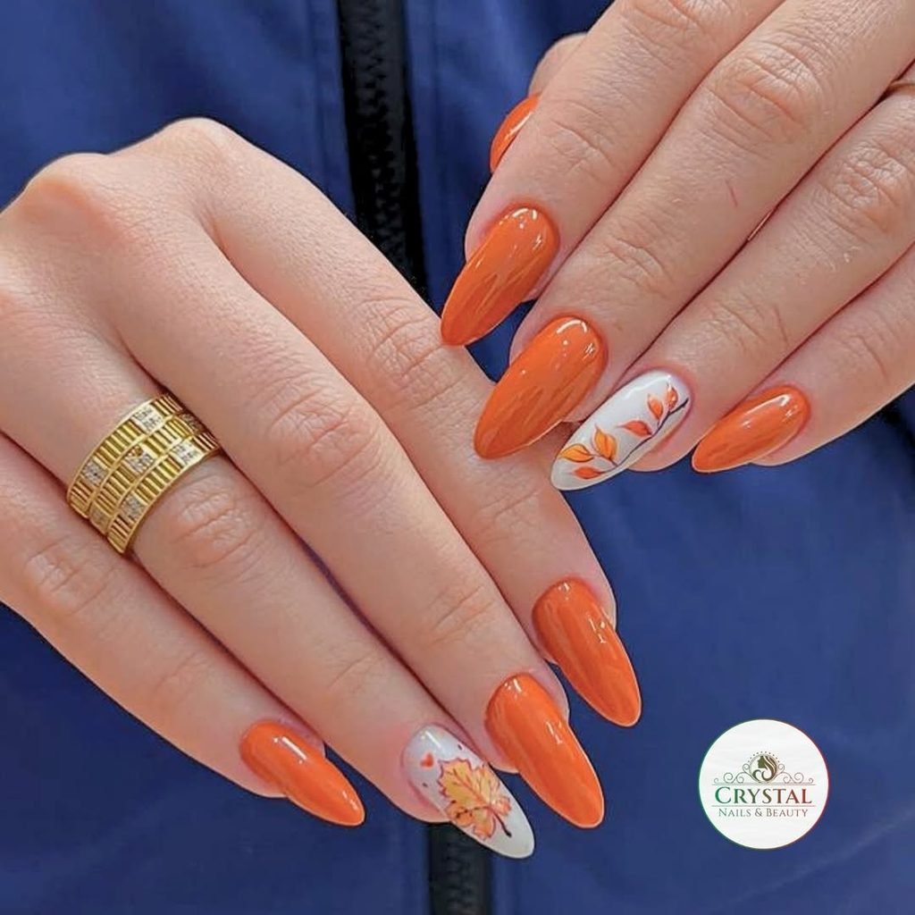 bright orange almond nails featuring autumn leaf nail art on white accent nails