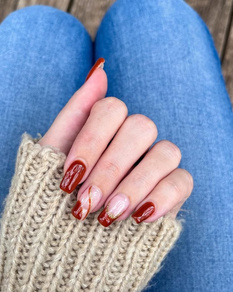 glossy reddish brown square nails with white and gold swirl accent details