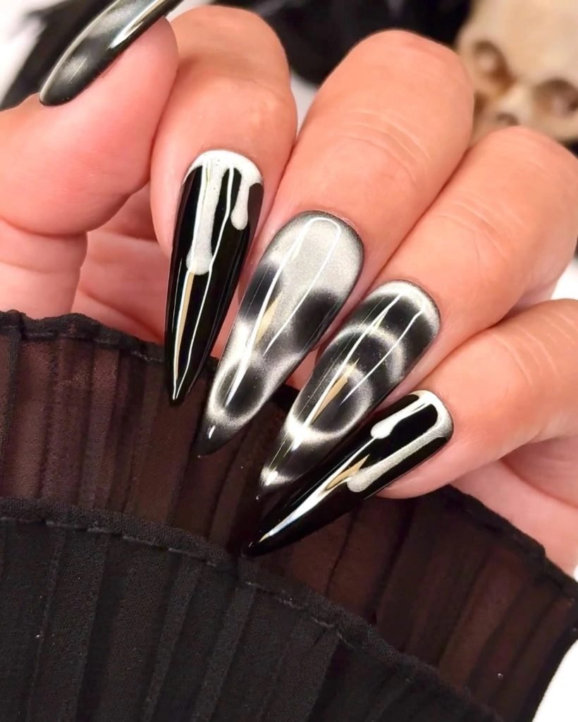 black stiletto cat eye nails with a white wave and dripping polish design