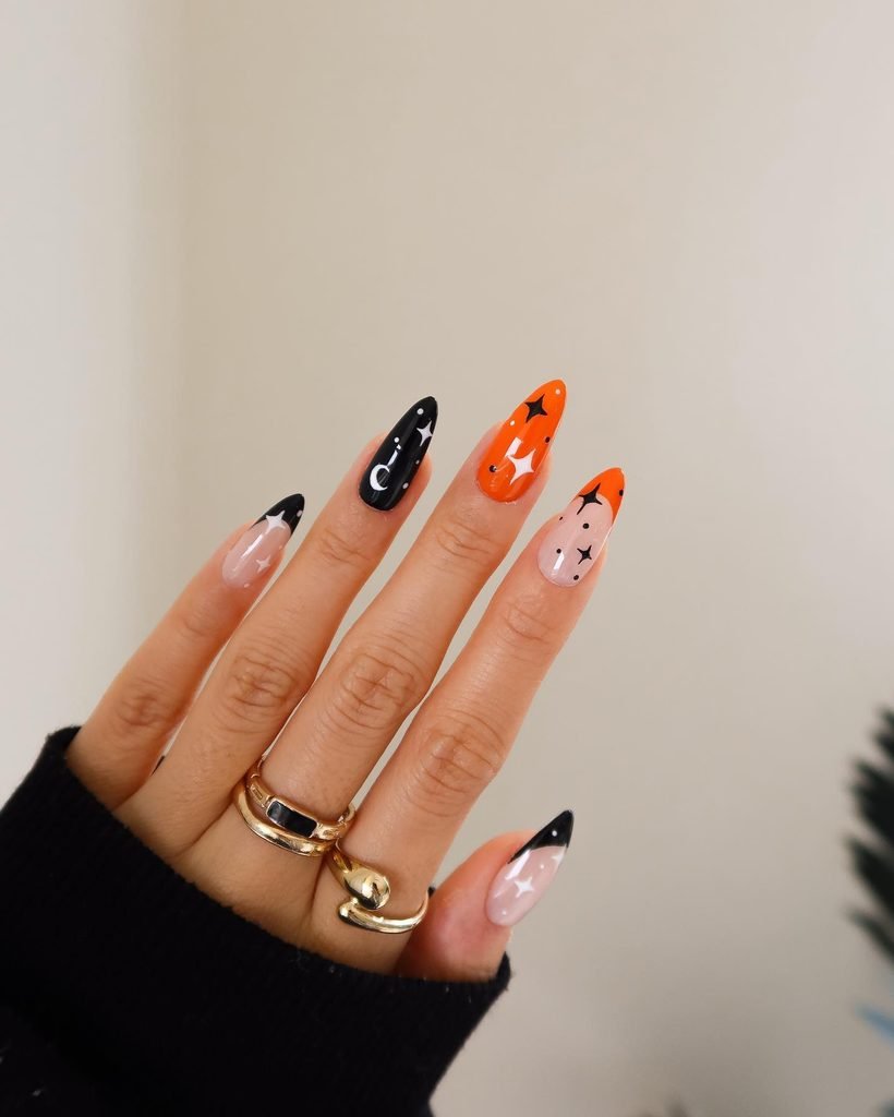 black and orange almond nails decorated with white stars and crescent moons