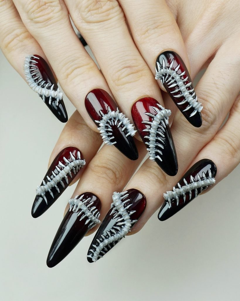 dark red and black stiletto nails featuring three dimensional white spine bone art
