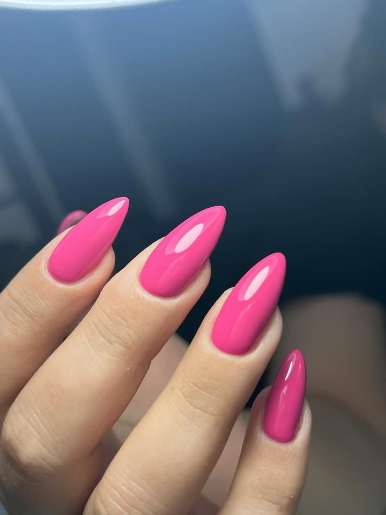 bright magenta stiletto nails on a single hand close up