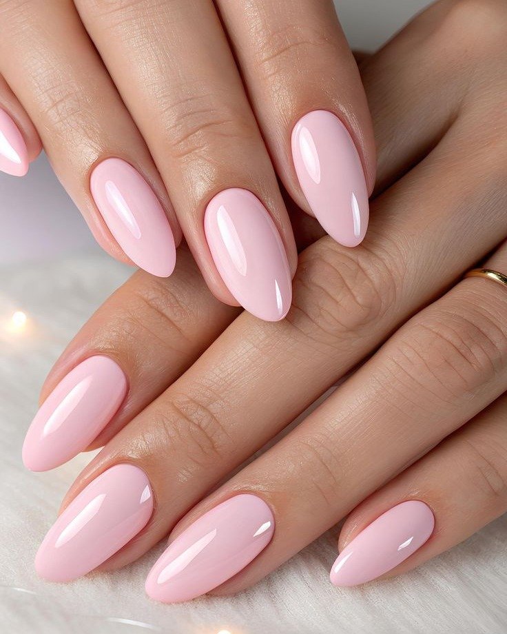 glossy light baby pink almond nails on two hands close up