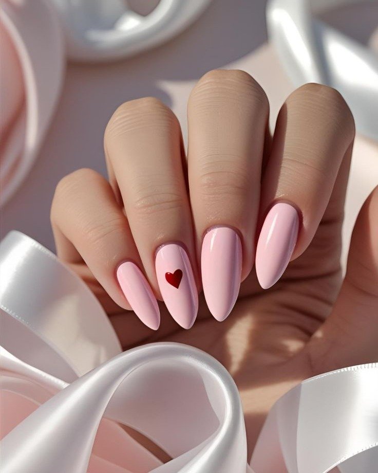 light pink almond nails with a small red heart on one finger