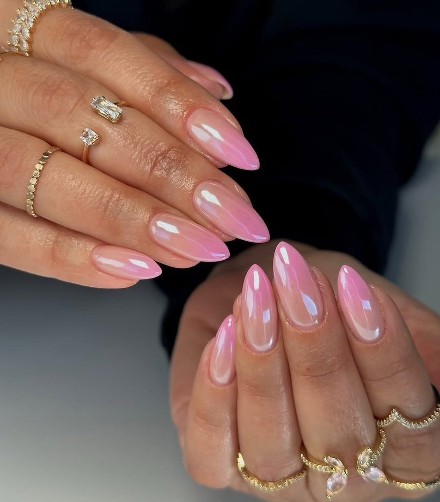 glossy pink chrome almond nails on hands with gold rings