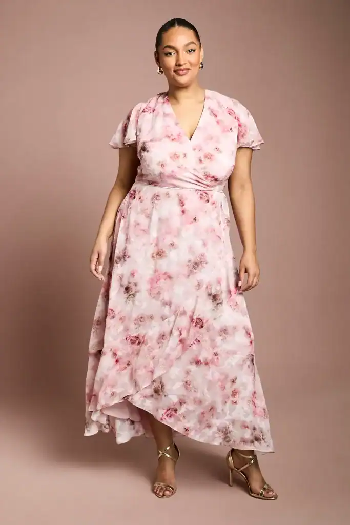 woman posing in a pink floral v-neck maxi dress with gold strappy heels
