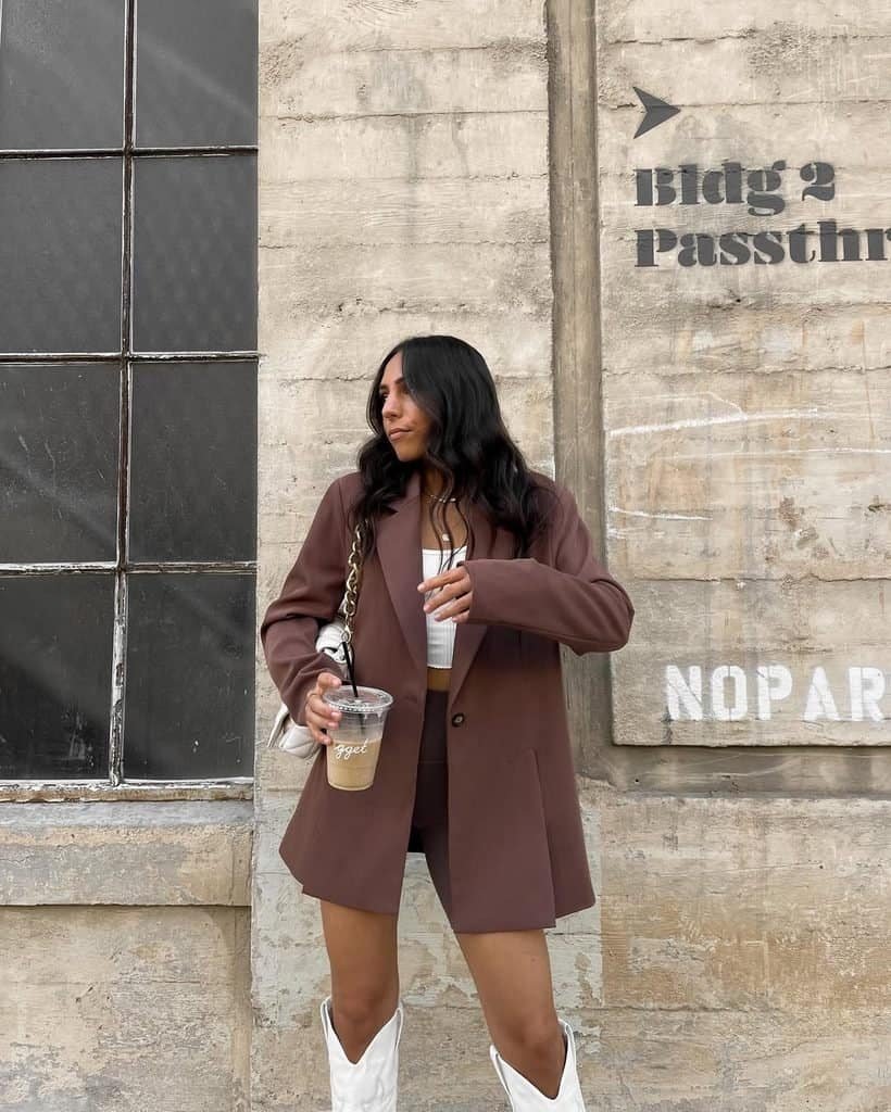 woman wearing brown oversized blazer and matching shorts set outdoors holding coffee