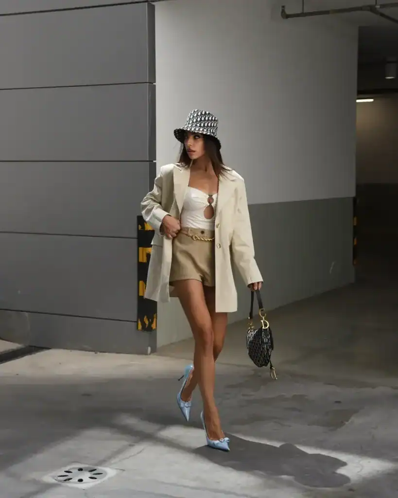 woman walking in cream oversized blazer tan shorts and patterned bucket hat