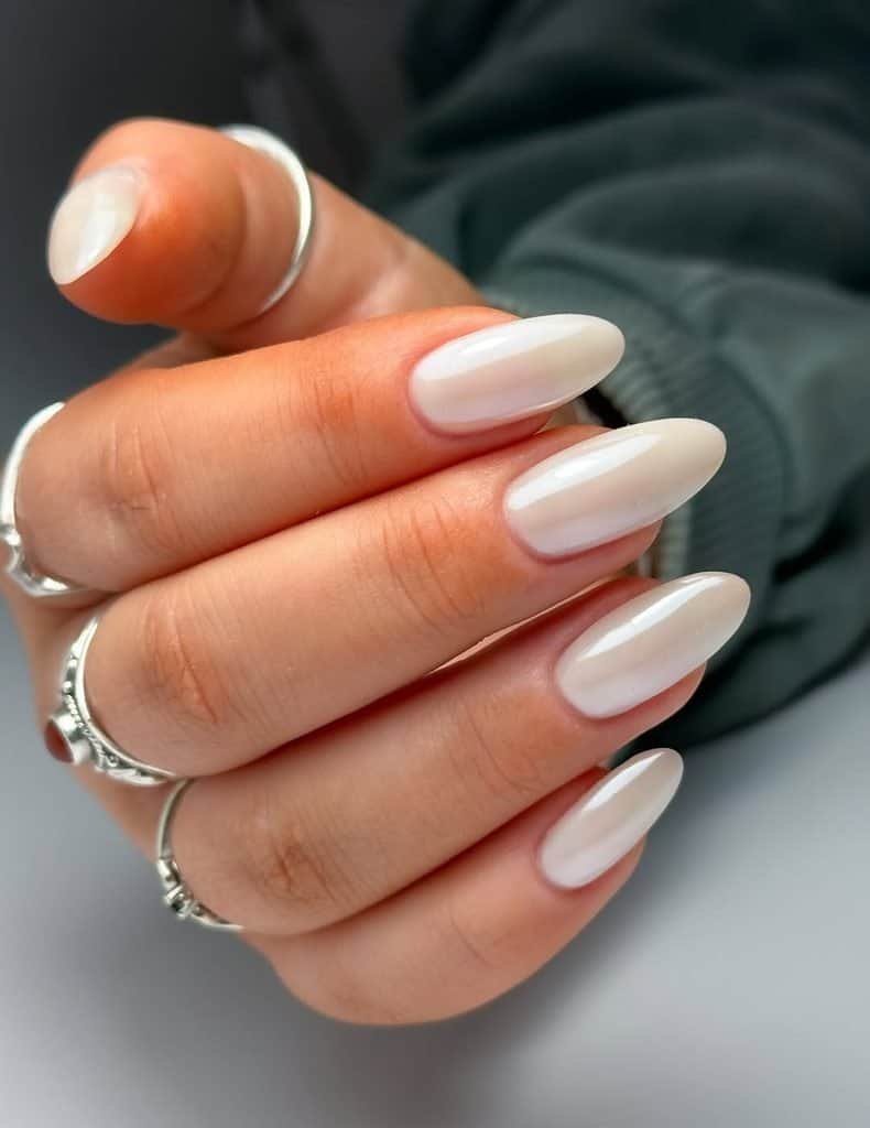 glossy milky white chrome polish on elegant medium length almond shaped nails