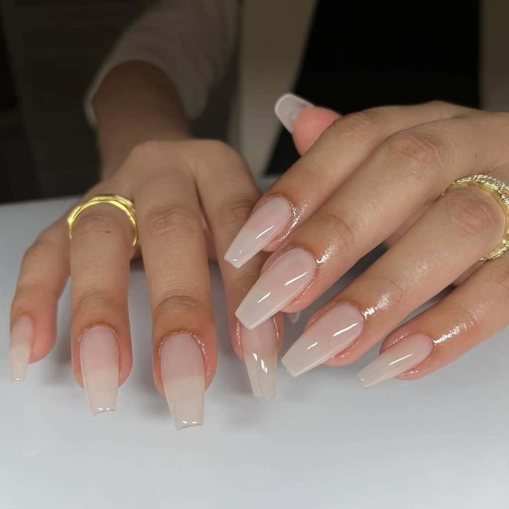 long translucent nude acrylic extensions styled in a glossy coffin shape
