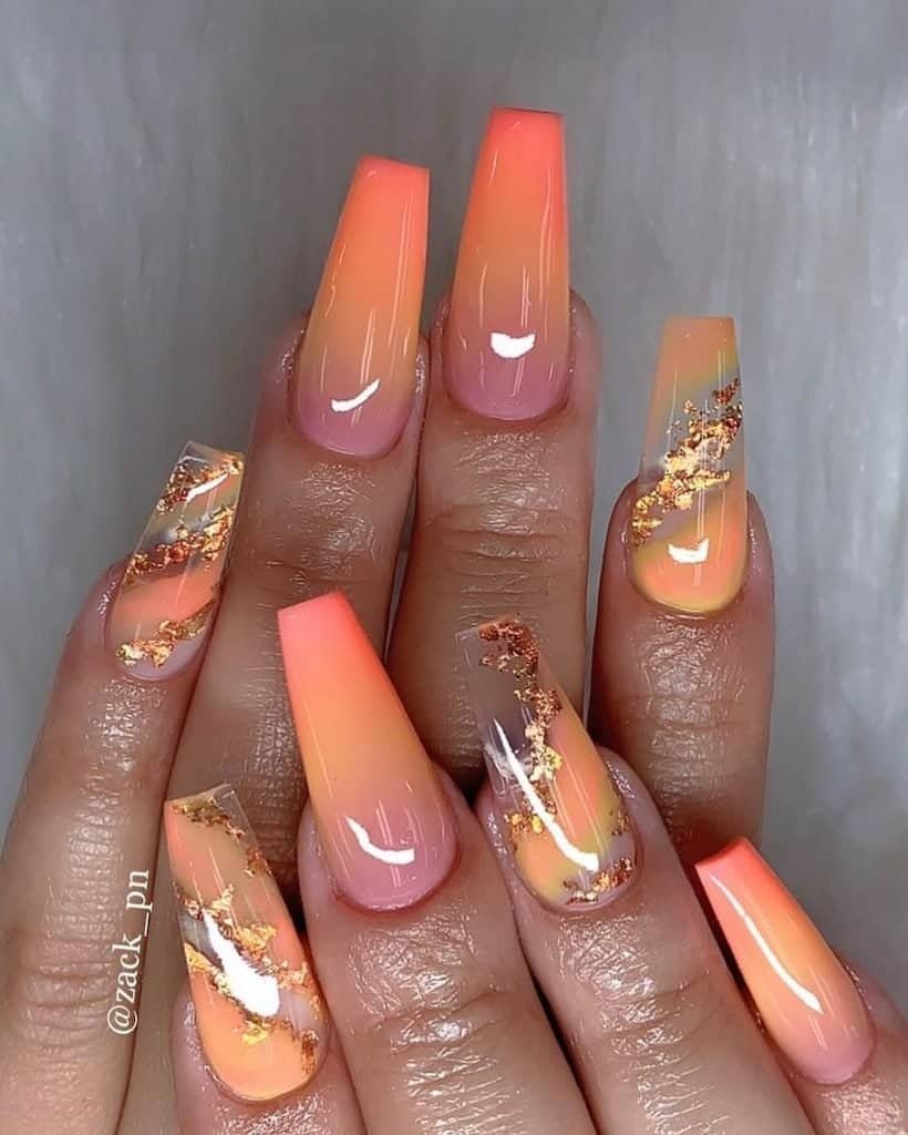 long coffin nails with orange ombre shading and decorative gold foil accents