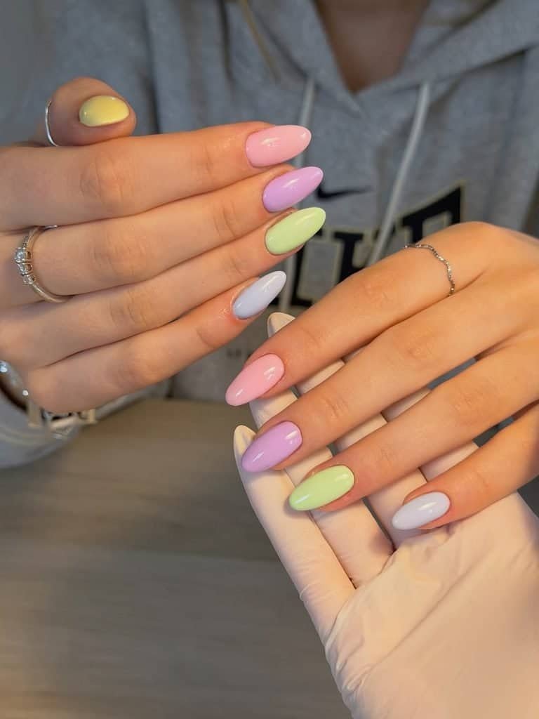 multicolored pastel manicure featuring pink purple green and blue polish on almond nails