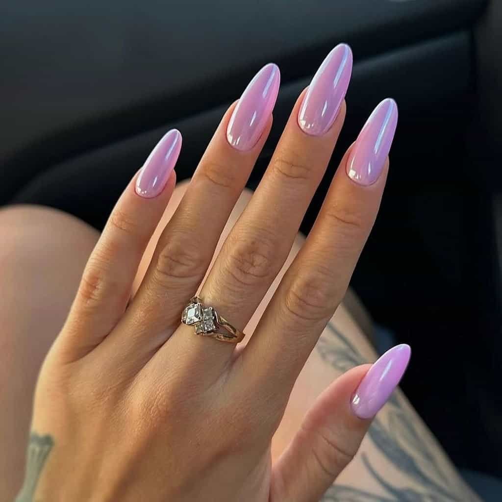 shimmering iridescent pink chrome nail extensions on a hand wearing a diamond ring