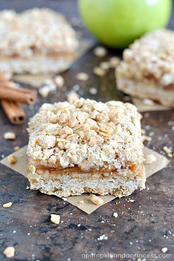 apple crumble bars topped with oats and cinnamon sticks on parchment paper