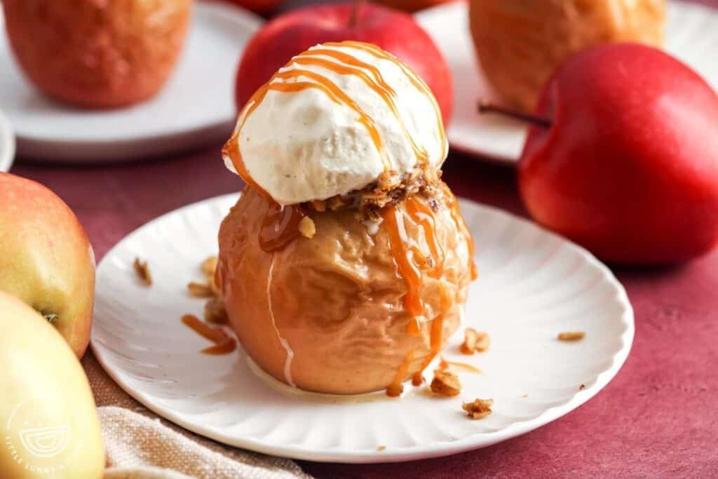 baked apple topped with vanilla ice cream and caramel drizzle on white plate